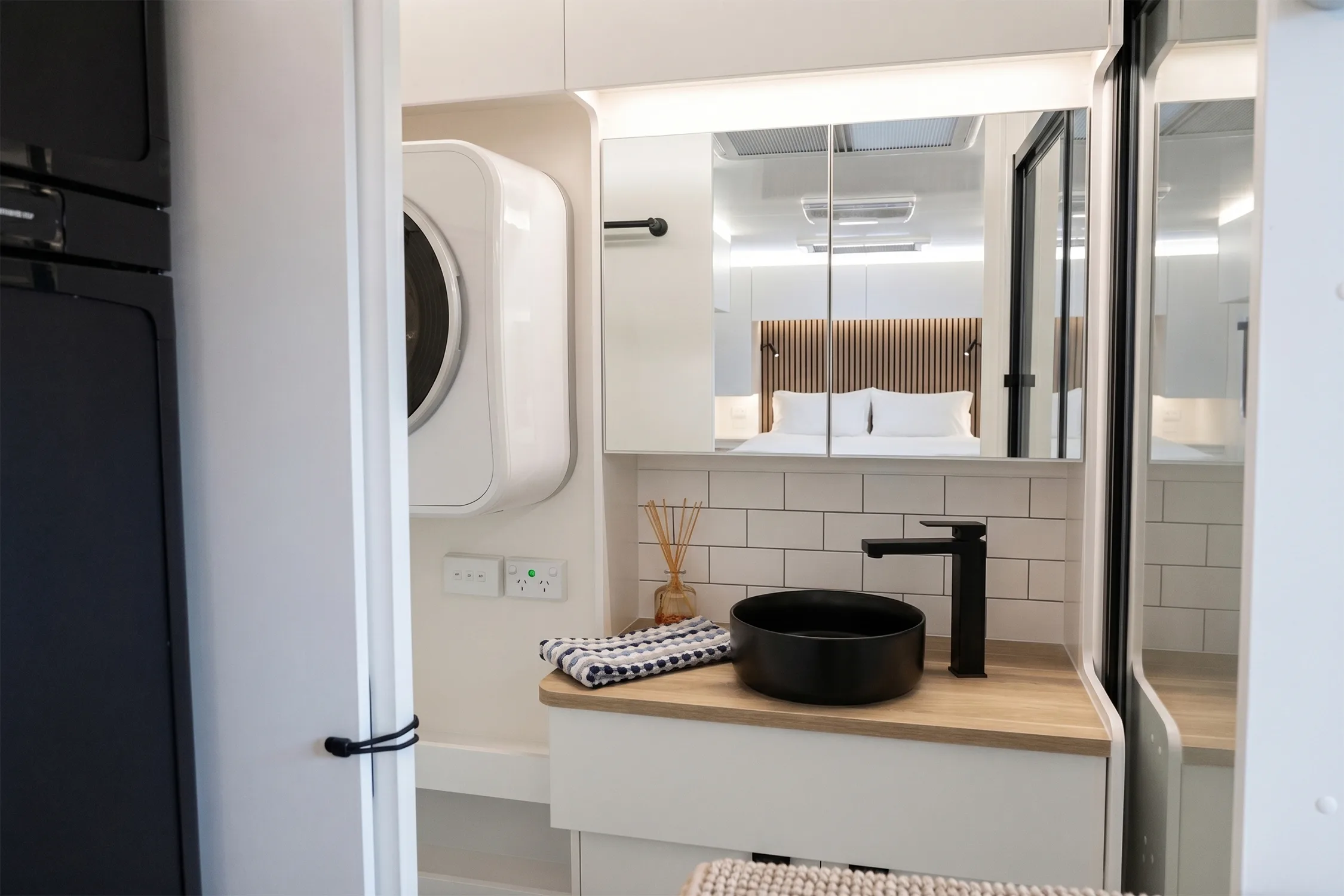 Manta Ray ensuite with matte black vessel basin, mirrored cabinet and washing machine